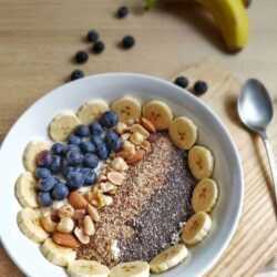 nutritious oatmeal plated in a bowl with fruit nuts and seeds.