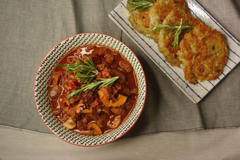 vegan German style goulash with soy protein chunks served with potato fritters