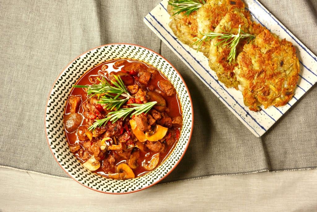 vegan German style goulash with soy protein chunks served with potato fritters