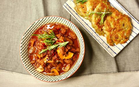 vegan German style goulash with soy protein chunks served with potato fritters