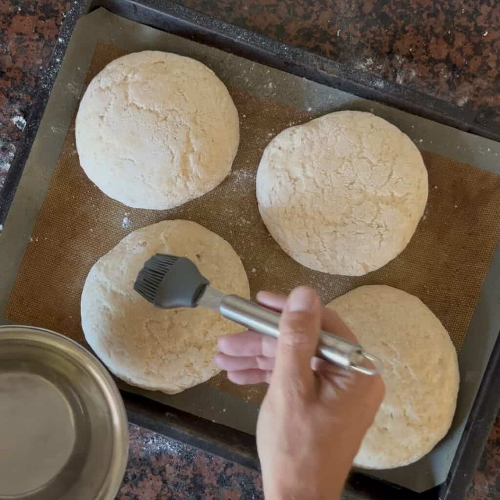 Water gets brushed on risen bread dough