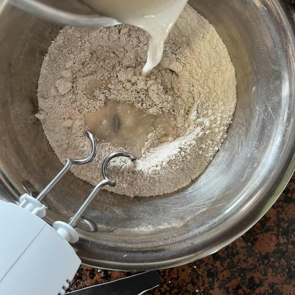 A photo showing yeast water being poured into a bowl with flowr.