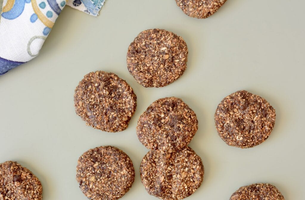 A photo of oatmeal cookies on a green surface with a kitchen towel.